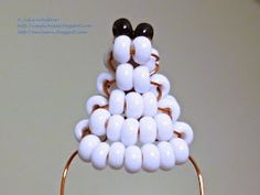 a close up of a white and black beaded object on a metal stand with gold rings