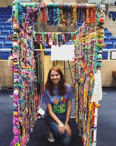 a woman kneeling down in front of a display of bracelets and necklaces hanging from the ceiling