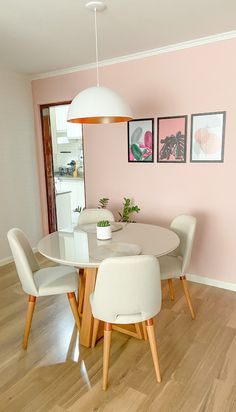 a dining room with pink walls and white chairs around a round table in the center