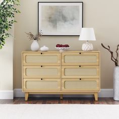 a dresser with two vases and a painting on the wall in front of it