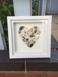 a heart made out of seashells in a white frame