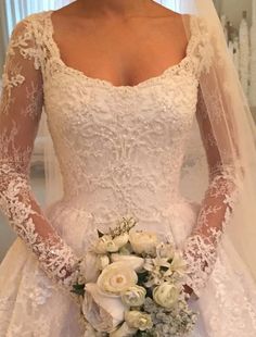 a woman in a wedding dress holding a bridal bouquet with white flowers on it