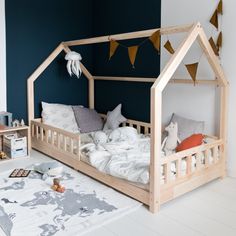 a child's bed made out of wood with a canopy and pillows on the floor