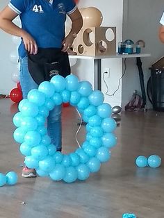 a man standing in front of a blue balloon arch with the letter o on it