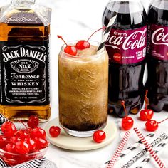 three bottles of jack daniels and two glasses with cherries