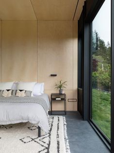 a bedroom with a large bed sitting next to a tall glass window on the wall