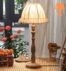 a lamp sitting on top of a table next to a basket filled with fruit and flowers