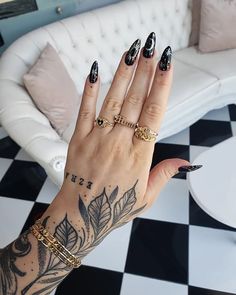 a woman's hand with black and white designs on it, holding onto a couch