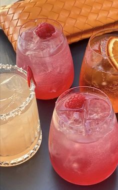 three glasses filled with different types of drinks and garnished with raspberries