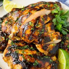 grilled chicken with cilantro and lime garnish on a white plate