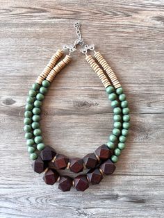 A lightweight beaded multi strand statement necklace made with dark brown and olive green wood beads and beige coconut wood beads. - Shortest strand is 20.5-22.5".- Stainless steel lobster claw clasp (gold stainless, sterling silver, gold filled are also available)- 2" Stainless steel extender chain- Lead free pewter multi strand connectors - Largest bead measures 20mm (.78")The length can be customized. The mannequin's neck size is 15". Larger quantities may be available. Please let us know how many you need.All DLD jewelry comes in a silver jewelry box for gift giving. We use the highest quality findings to ensure a piece that will last for years to come. DLD jewelry comes with a lifetime guarantee. This necklace is handmade in the USA. Dana LeBlanc Designs- Handmade Jewelry Olive Green Jewelry, Green Statement Necklace, Box For Gift, Coconut Wood, Silver Jewelry Box, Beads Mala, Wood Bead Necklace, Wood Necklace, Green Jewelry