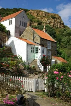 a white house sitting on the side of a hill next to a lush green hillside