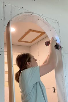 a woman is painting the ceiling in an unfinished room