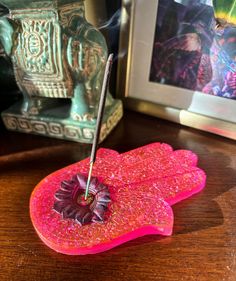 a pink object sitting on top of a wooden table next to a framed photo and an ornate vase