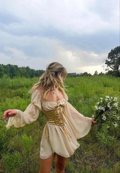 a woman in a dress is walking through the grass