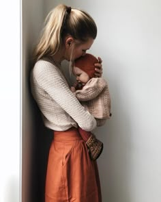 a woman holding a baby in her arms while leaning against a wall with the words interest written on it