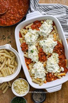 pasta and sauce in a white casserole dish on a wooden table with other ingredients