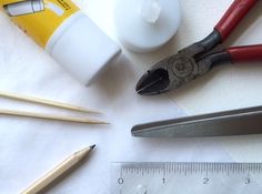 some tools are sitting on a table next to a ruler, pencils and glue