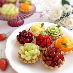 small fruit tarts on a plate with flowers in the backgroufground