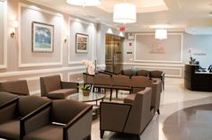 an empty waiting room with chairs and tables in the center, along with pictures on the wall