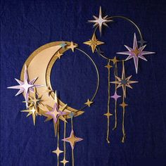 a crescent with stars hanging from it on a blue background next to a clock and wind chime