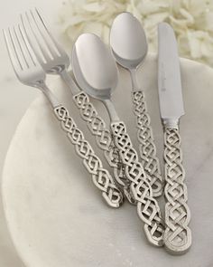 four forks, two spoons and one knife on a white plate with flowers in the background