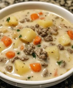 a bowl of soup with meat and potatoes in it on a granite countertop top