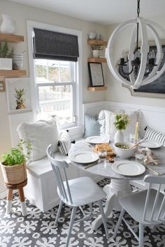 a dining room table with white chairs and plates on it