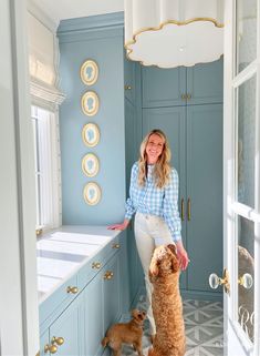 a woman standing in a kitchen with two dogs