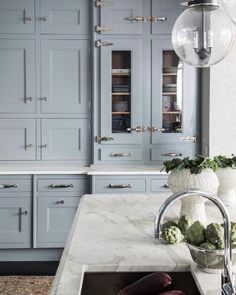 a kitchen with blue cabinets and marble counter tops, along with a sink in the center