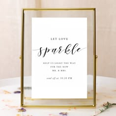 a sign that says let love sparkle in black ink on a white background with gold frame