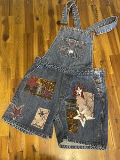 an old pair of denim overalls with patchwork and stars on them, sitting on a wooden floor