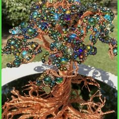 a tree made out of wire and beads on top of a potted planter