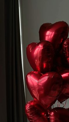 a bunch of red heart shaped balloons in front of a window