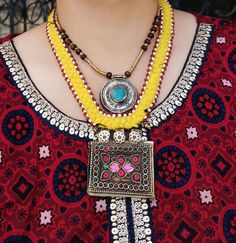 Unique Pashtun tribal Necklace Handmade by a group of women with fabric and vintage coins. Description: One of a kind Handmade ethnic necklace is attached to a fabric base using metallic beads.One large metallic tube bead is attached to metal hooks and beads,that are then connected to vintage amulet pendant,beautifully weaved in red glass beads. Button closure at the back. Free shipping in the US Bohemian Pendant Jewelry For Rituals, Yellow Bohemian Long Necklace, Bohemian Pendant Necklaces For Festivals, Bohemian Pendant Necklaces For Rituals, Handmade Pendant Necklace For Navratri, Bohemian Jewelry With Large Pendant For Festivals, Bohemian Large Pendant Jewelry For Festivals, Bohemian Multicolor Jewelry For Navratri, Bohemian Beaded Pendant Necklace For Rituals