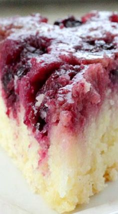 a close up of a piece of cake on a plate with blueberries and raspberry sauce