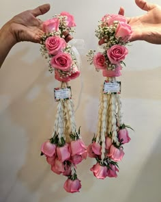 two hands are holding pink roses and other flowers