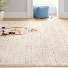 a child's toy train set sitting on top of a rug in front of a window