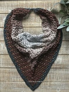 a crocheted scarf is hanging on a wooden wall next to a potted plant