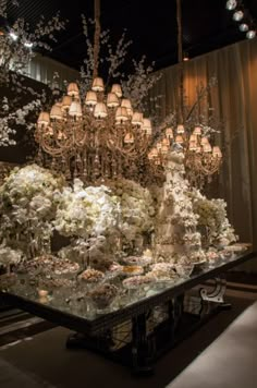 an elaborate chandelier hangs from the ceiling above a table with flowers on it