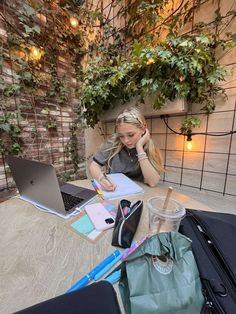 a woman sitting at a table with a laptop and notebook