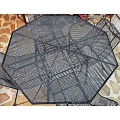 an outdoor table that is made out of metal mesh and has been placed on the ground