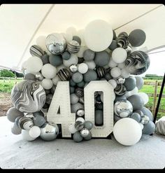 the number 40 is made out of balloons and marbles in white, grey and silver