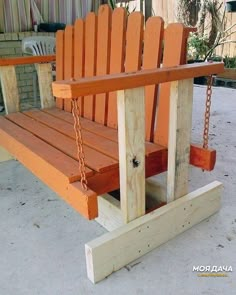 a wooden swing with chains attached to it on the concrete flooring in front of a building