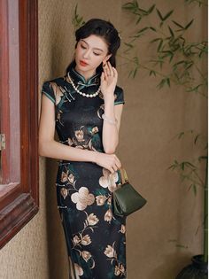 Step into elegance with this luxurious black silk qipao adorned with an exquisite floral design. The dress features a high Mandarin collar and traditional frog buttons, giving it a refined, authentic look. The rich green floral motif, interspersed with delicate cream and gold blossoms, adds a touch of nature-inspired beauty, making it perfect for formal occasions, evening events, or as a statement piece for special gatherings. Material: 90% Mulberry Silk, 10% Spandex Size Guide: Please note Asia Elegant Black Cheongsam For Spring, Traditional Black Dress With Floral Print, Elegant Floral Print Cheongsam With Stand Collar, Traditional Black Floral Print Dress, Elegant Green Cheongsam With Stand Collar, Elegant Fitted Cheongsam With Floral Print, Elegant Green Dress With Stand Collar, Green Elegant Cheongsam With Stand Collar, Traditional Floral Print Formal Dress