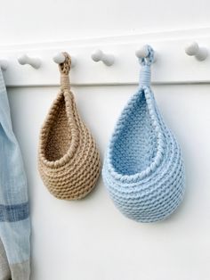 two crocheted baskets hanging from hooks on a white coat rack, one blue and one beige