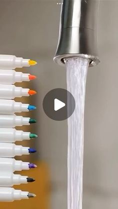 a faucet with water running from it and colored markers on the wall next to it