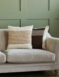 a couch with two pillows on top of it in front of a green painted wall