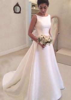 a woman in a white wedding dress is looking at her reflection in the mirror while holding a bouquet