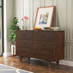 a wooden dresser sitting in a living room next to a potted plant